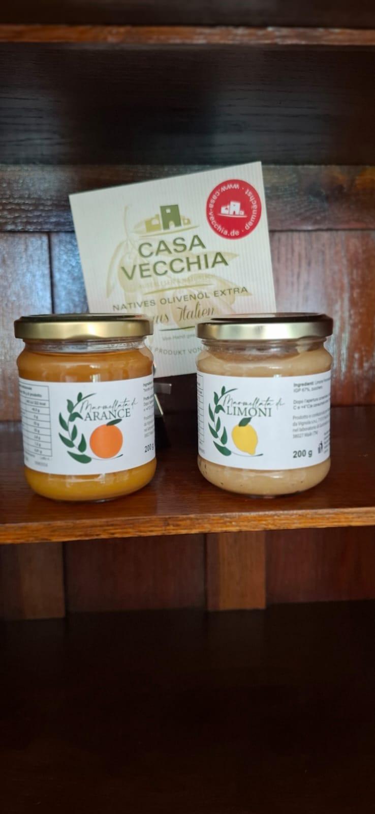 Two jars of orange and lemon jam on a wooden shelf, with a Casa Vecchia box in the background behind them.
